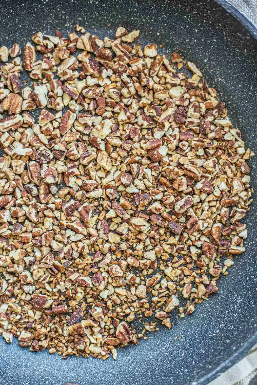 Process shot of toasting pecans in a pan