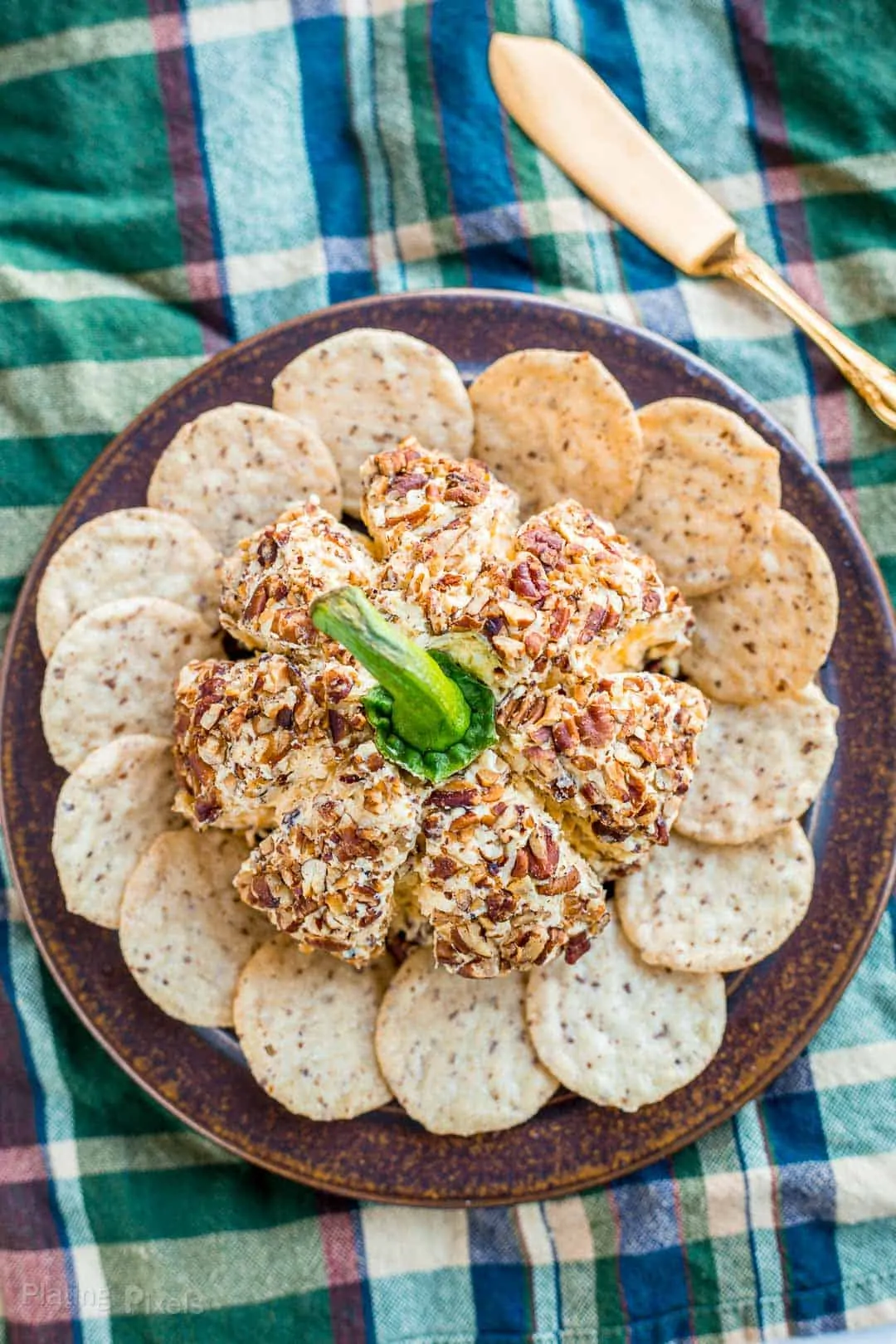 Overhead shot of a Pumpkin Cheese Ball on a plate surrounded by crackers