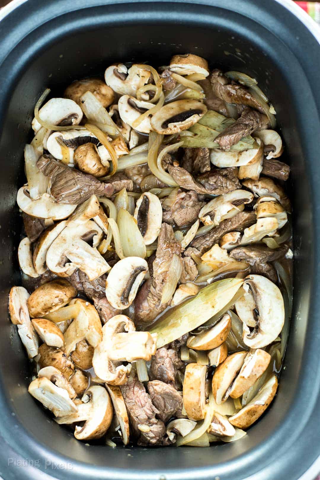 Steak and mushrooms in a slow cooker to make Slow Cooker Beef Stroganoff