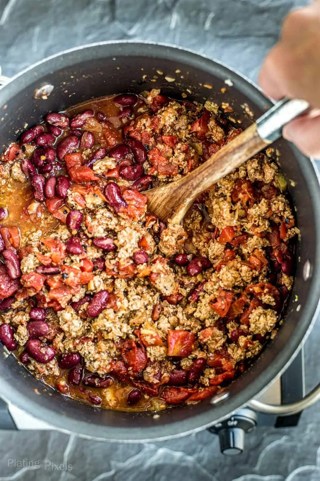 Process shot of stirring together turkey chili ingredients in a pot