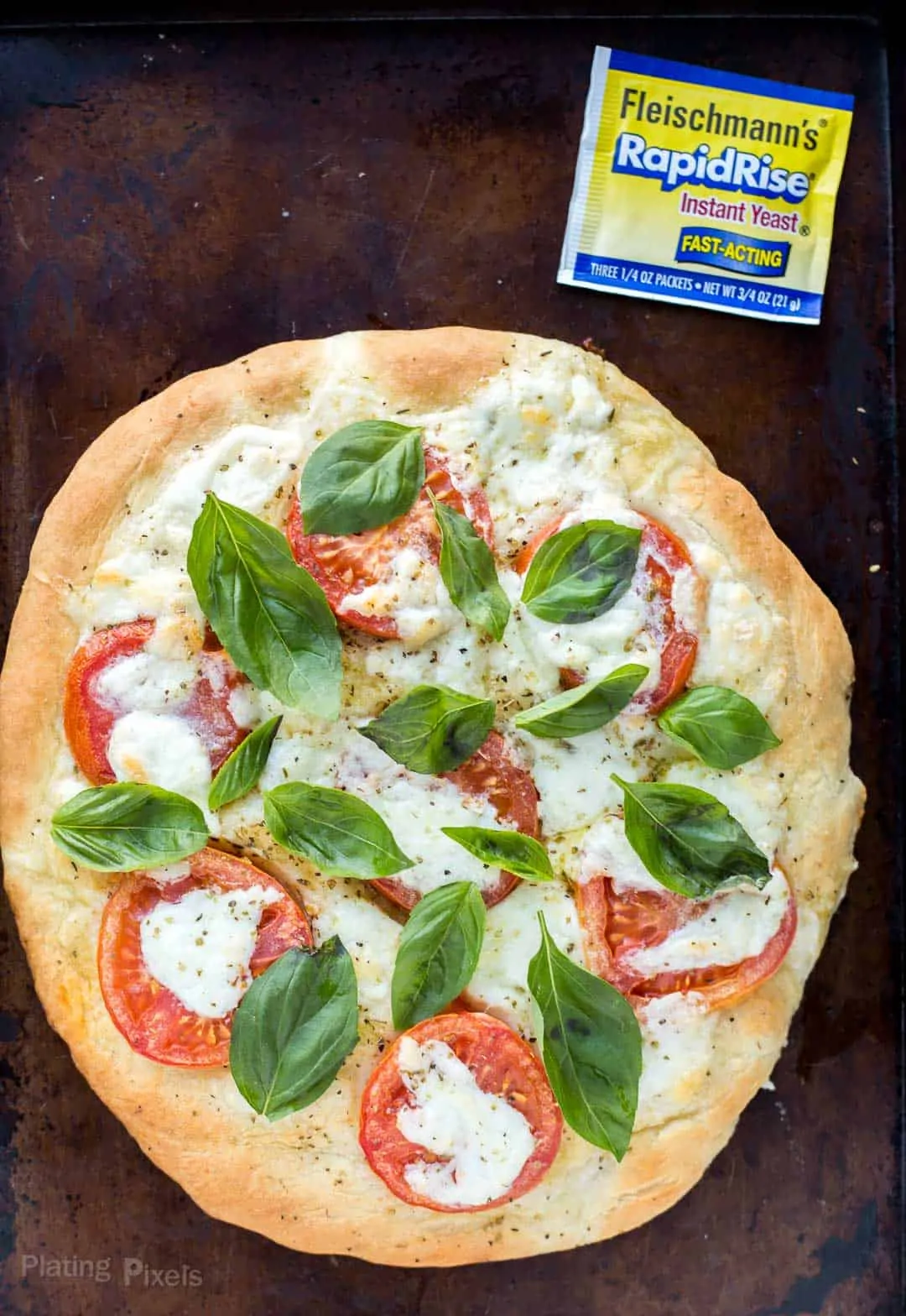 Caprese pizza on a baking dish next to package of rapid rise yeast