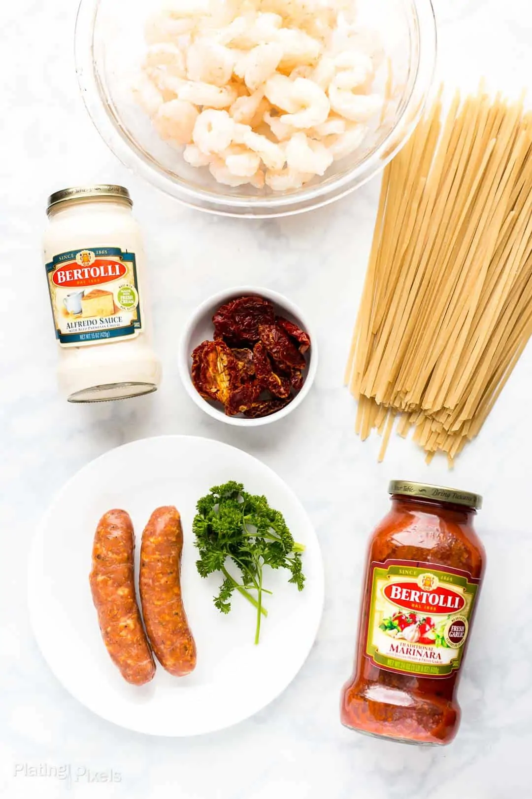 Ingredients to make Shrimp and Sausage Spaghetti with Rosa Sauce prepped on a white counter