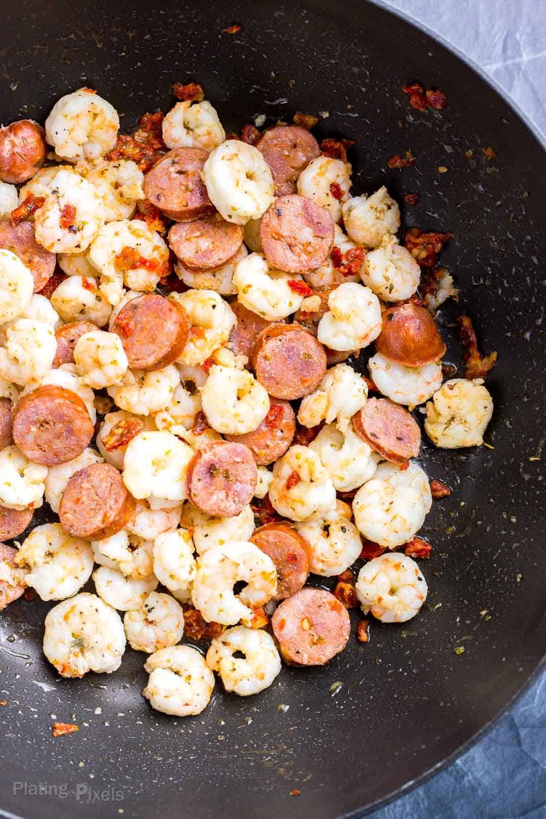Shrimp and sausage slices cooking in pan