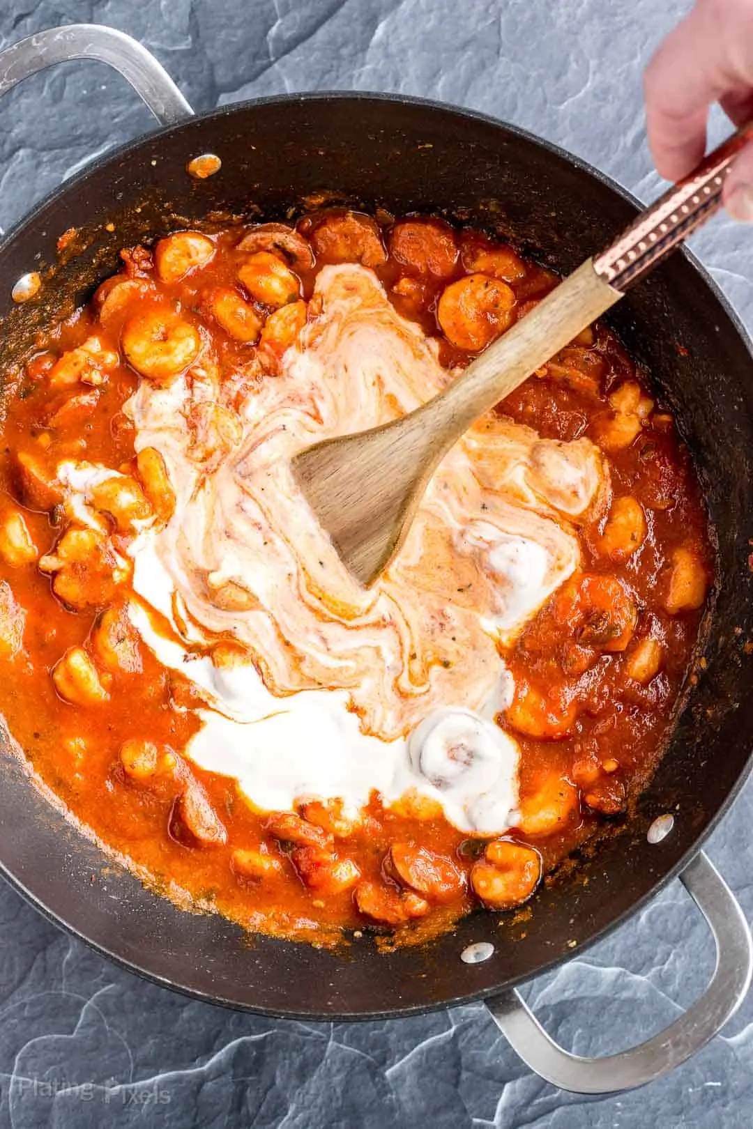 Process shot of stirring together marina and Alfredo to make rosa sauce