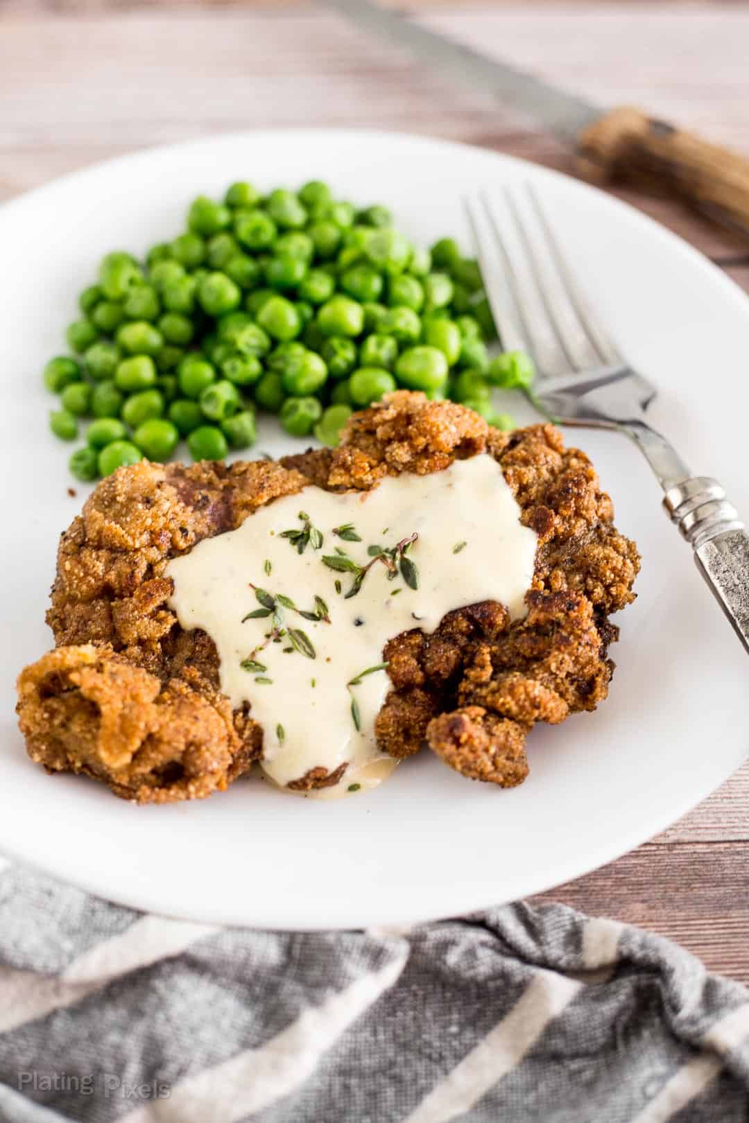 Keto Chicken Fried Steak on a plate served with green peas