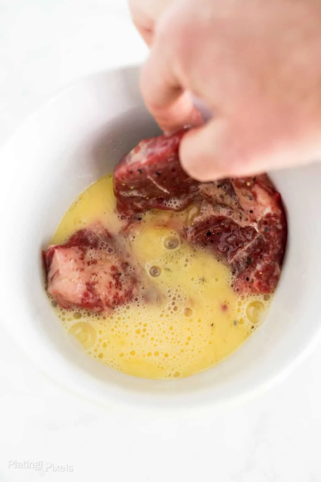 Process shot of dipping a cube steak into eggs