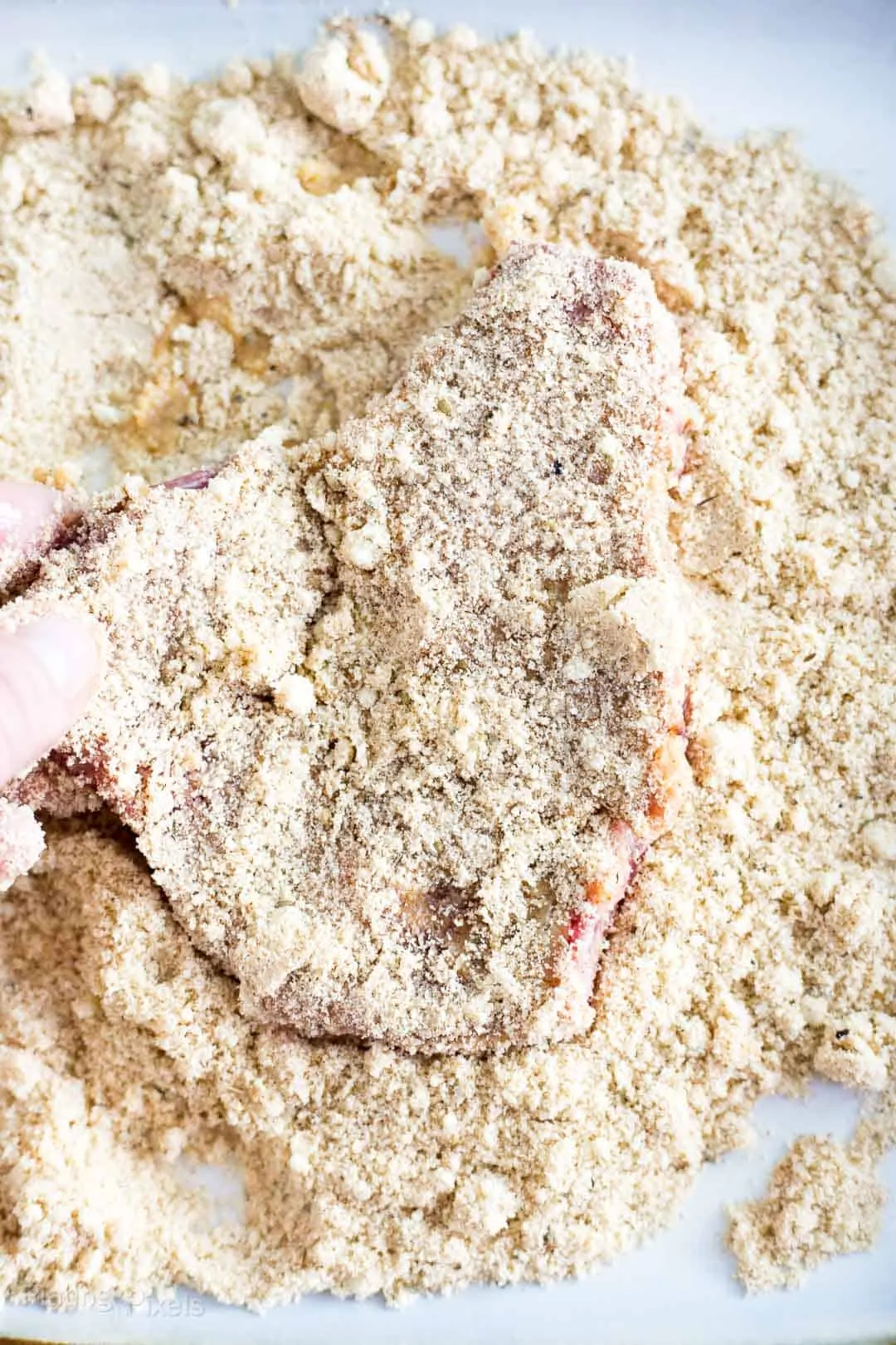 Process shot of coating the other side of a cube steak into breading