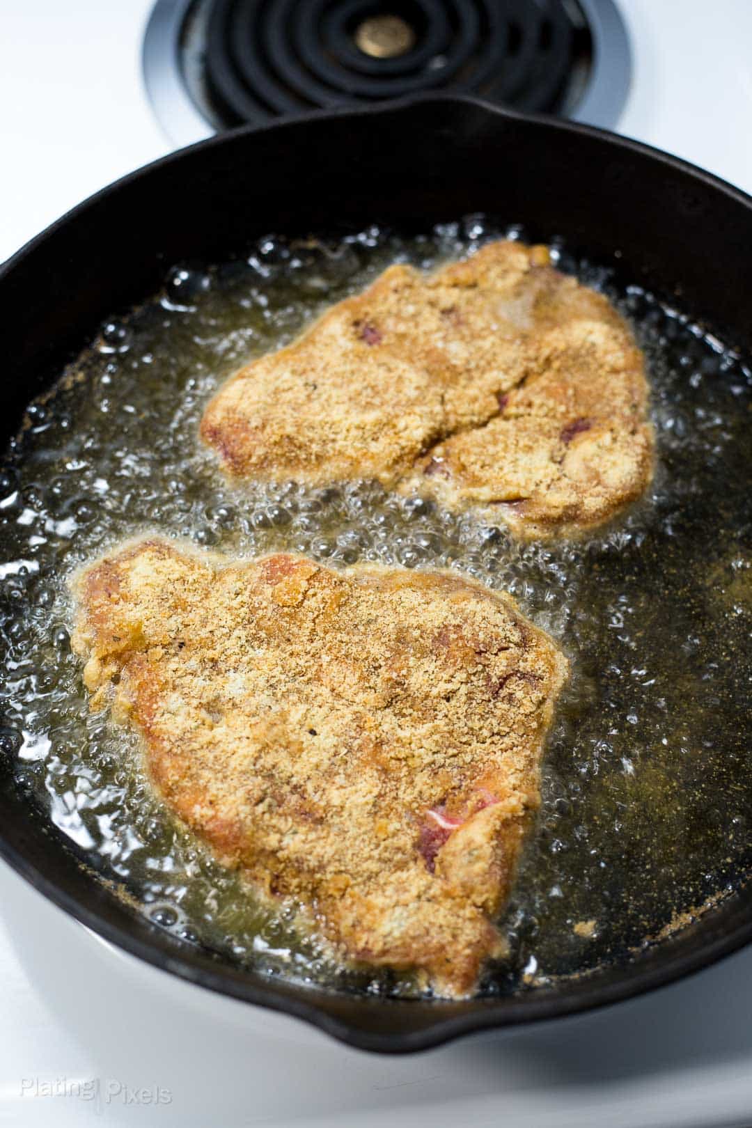 Process shot of Chicken Fried Steak frying in a pan