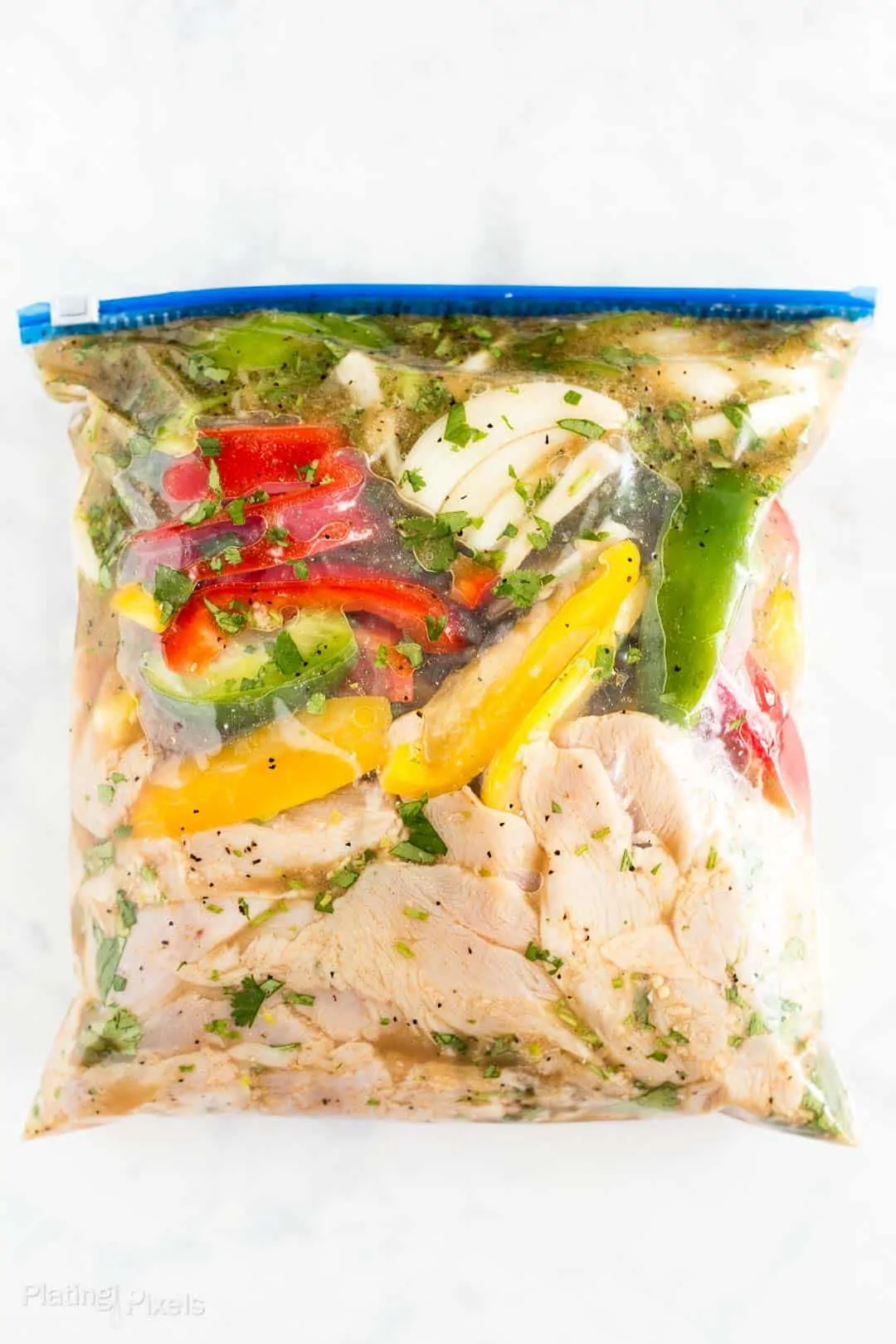 Process shot of chicken and vegetables marinating in a bag to make fajitas