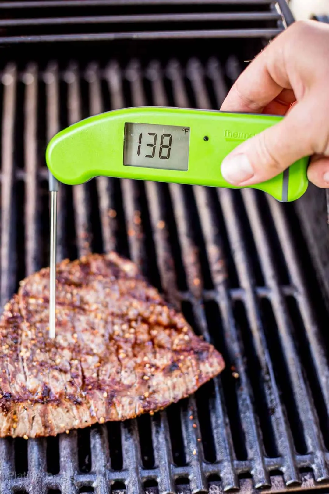 Checking the temperature of a London Broil on the grill with a digital thermometer