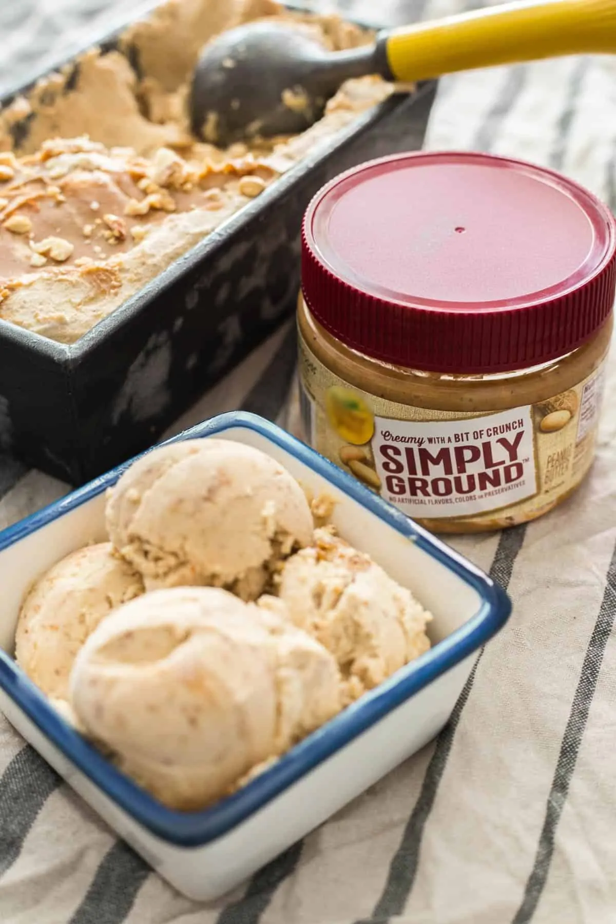 Peanut Butter Ice Cream scoops in a bowl next to a jar of peanut butter