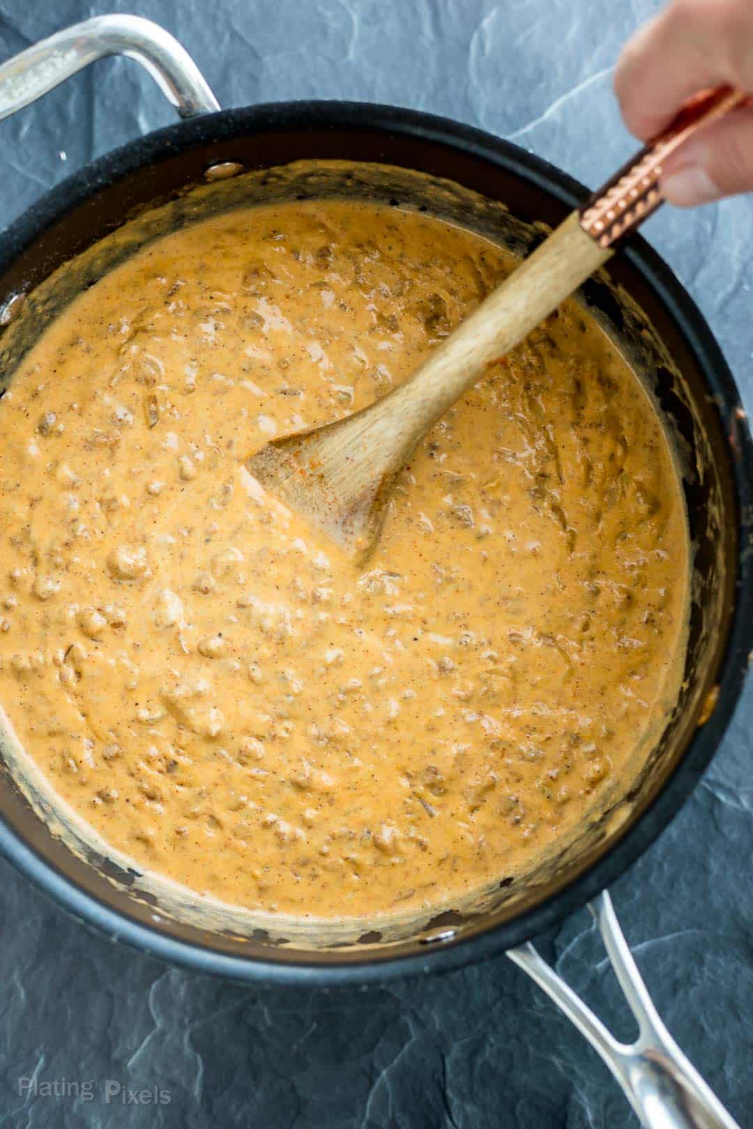 Chile chorizo cheese sauce being stirred in a large pot