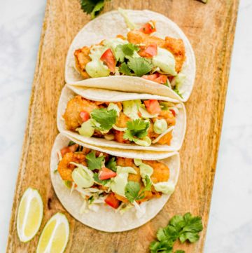 Three prepared Beer Battered Fish Tacos on a serving board