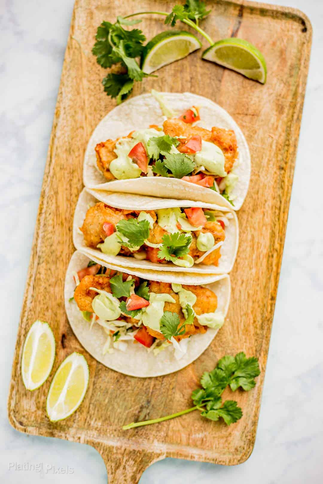 Three prepared Beer Battered Fish Tacos on a serving board
