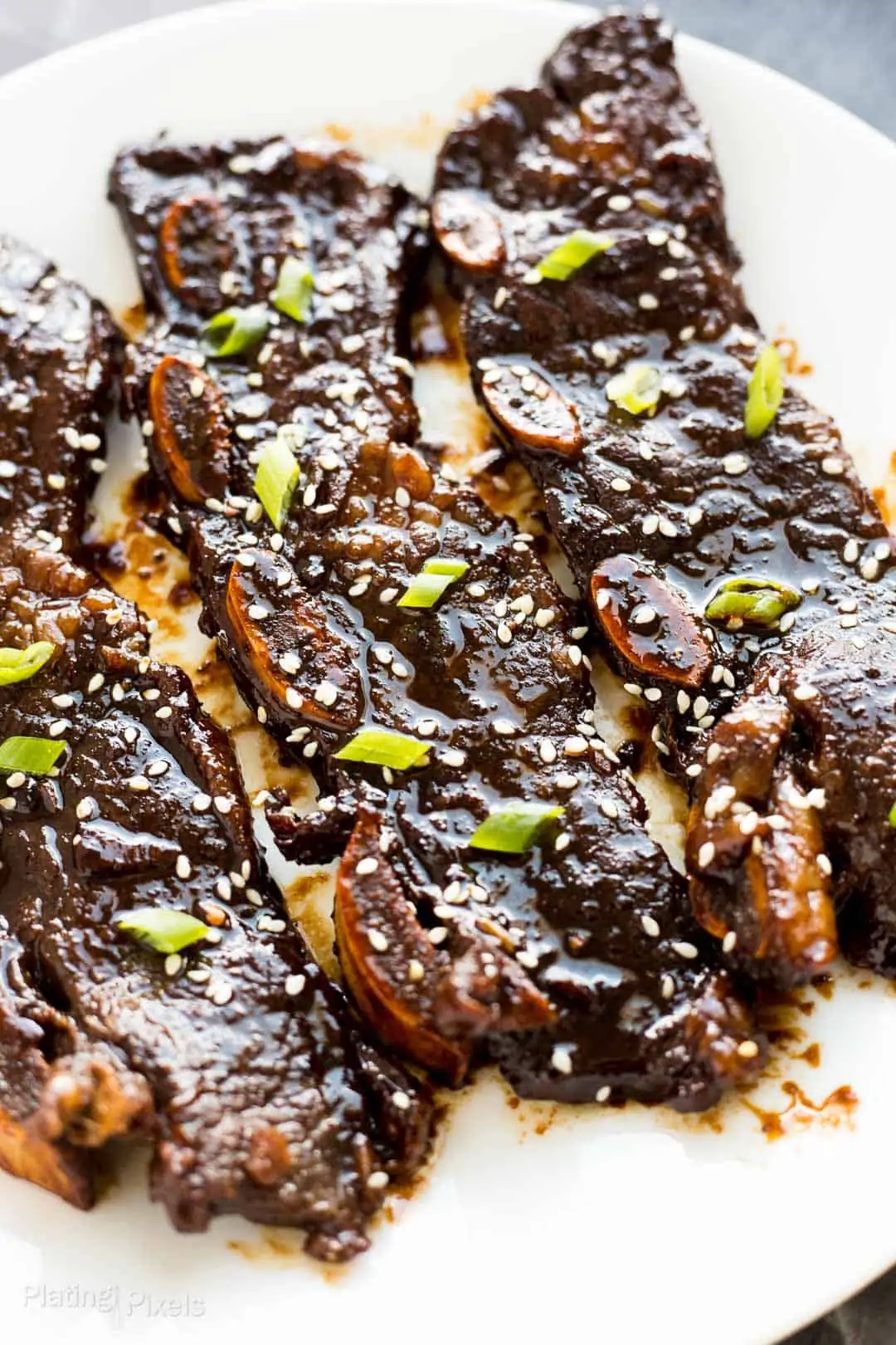 Close up of Kalbi Korean Short Ribs garnished with sesame seeds and green onions