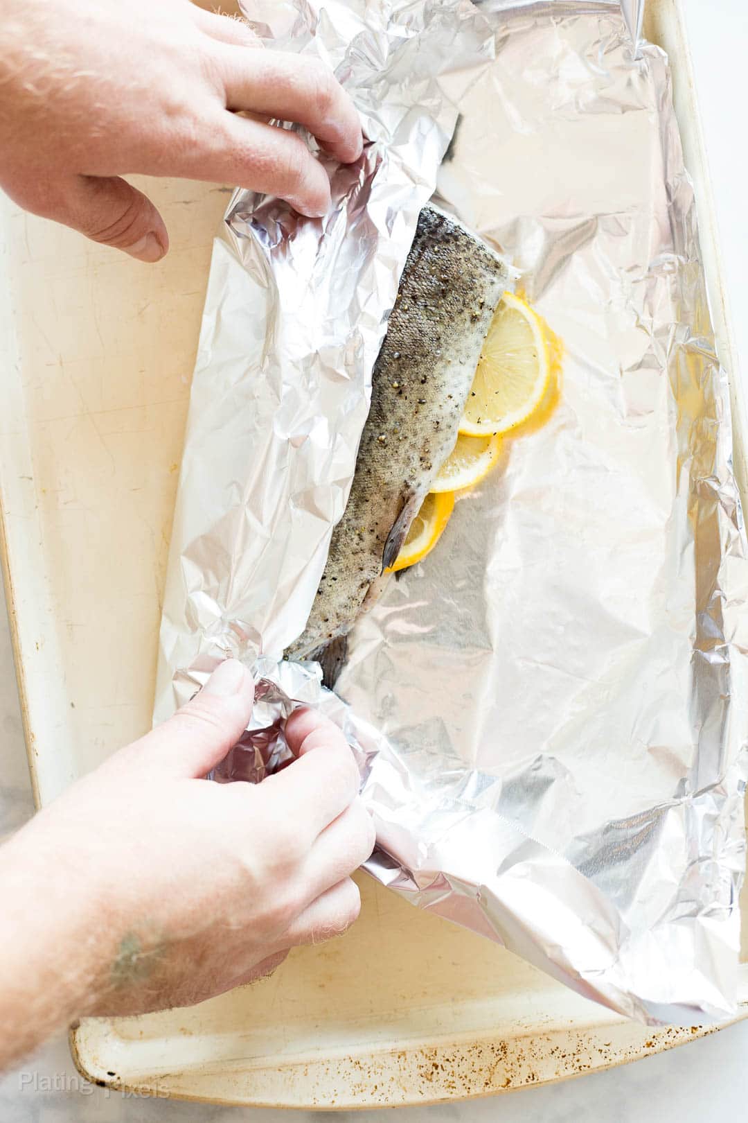 Process shot of sealing a whole trout in foil