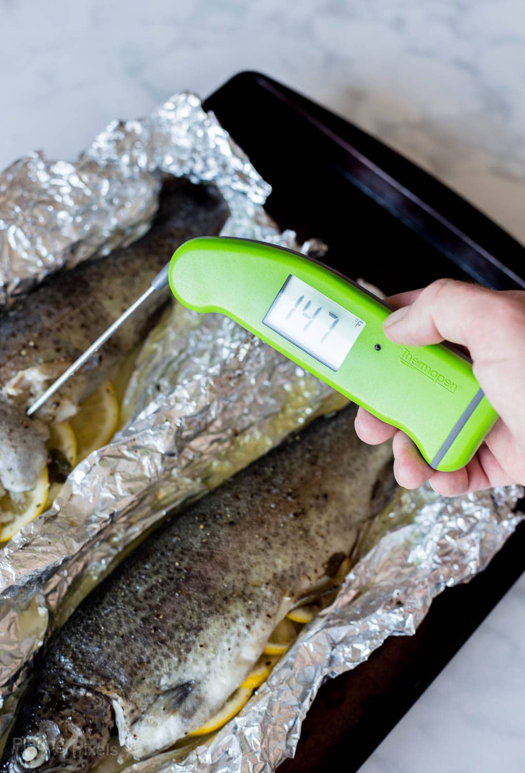 Using a digital thermometer to check the temperature of baked trout