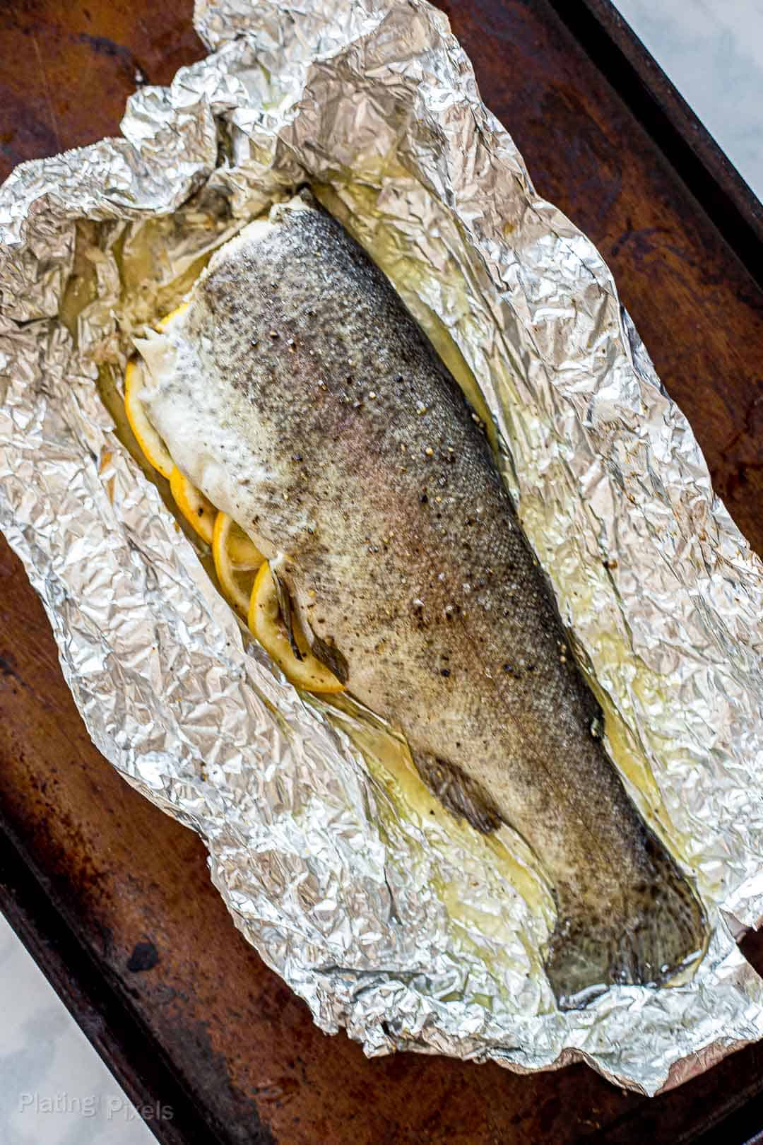 Oven baked trout with head removed on a baking sheet