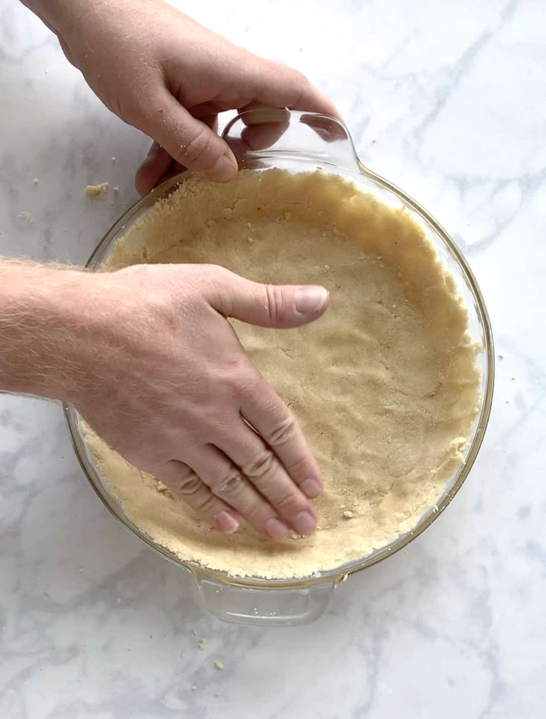 Process shot of pressing almond flour dough into a pie pan