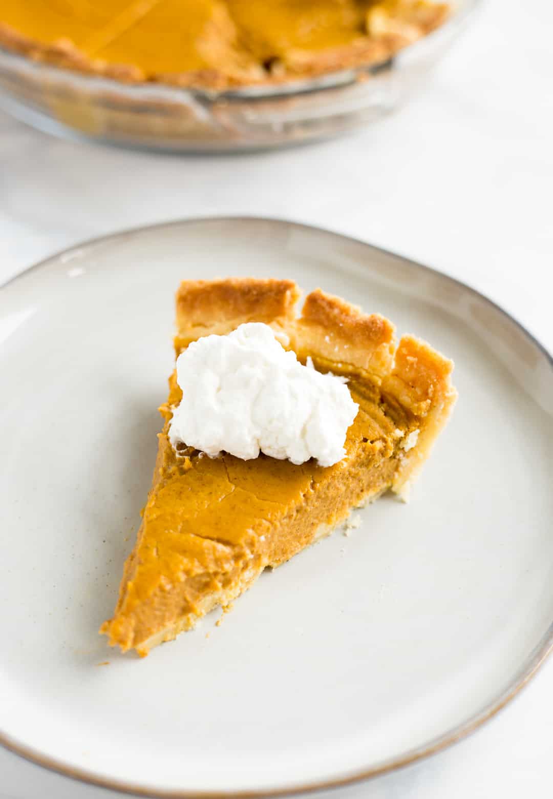 Slice of Keto Pumpkin Pie on a plate topped with whipped cream