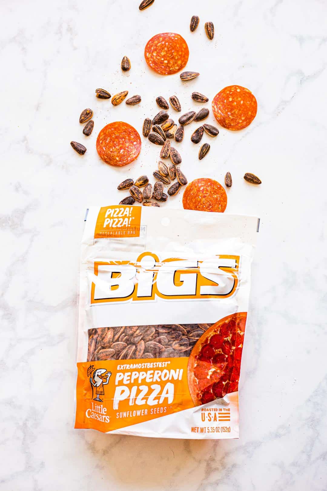Bigs Pepperoni Pizza Sunflower Seeds in bag next to pepperoni slices