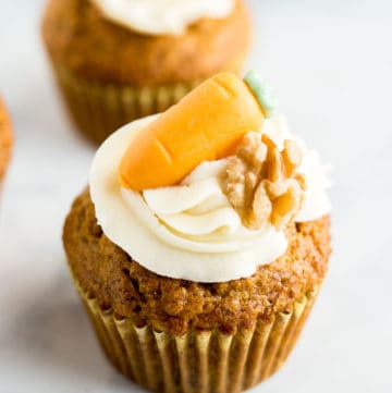 Close up of a Carrot Cake Cupcake topped with cream cheese frosting and marzipan carrot