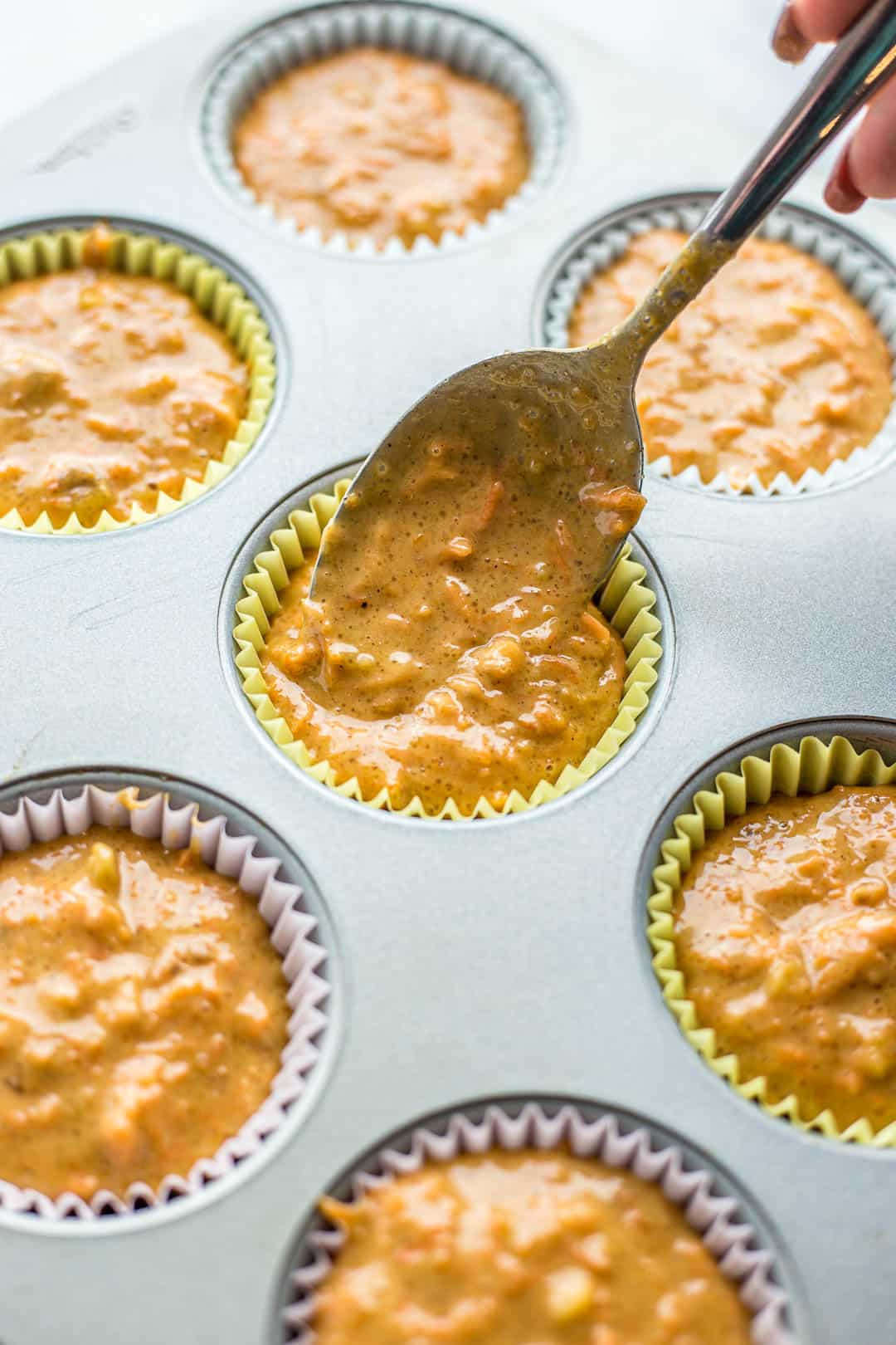 Process shot of adding cupcake batter to parchment liners in cupcake pan