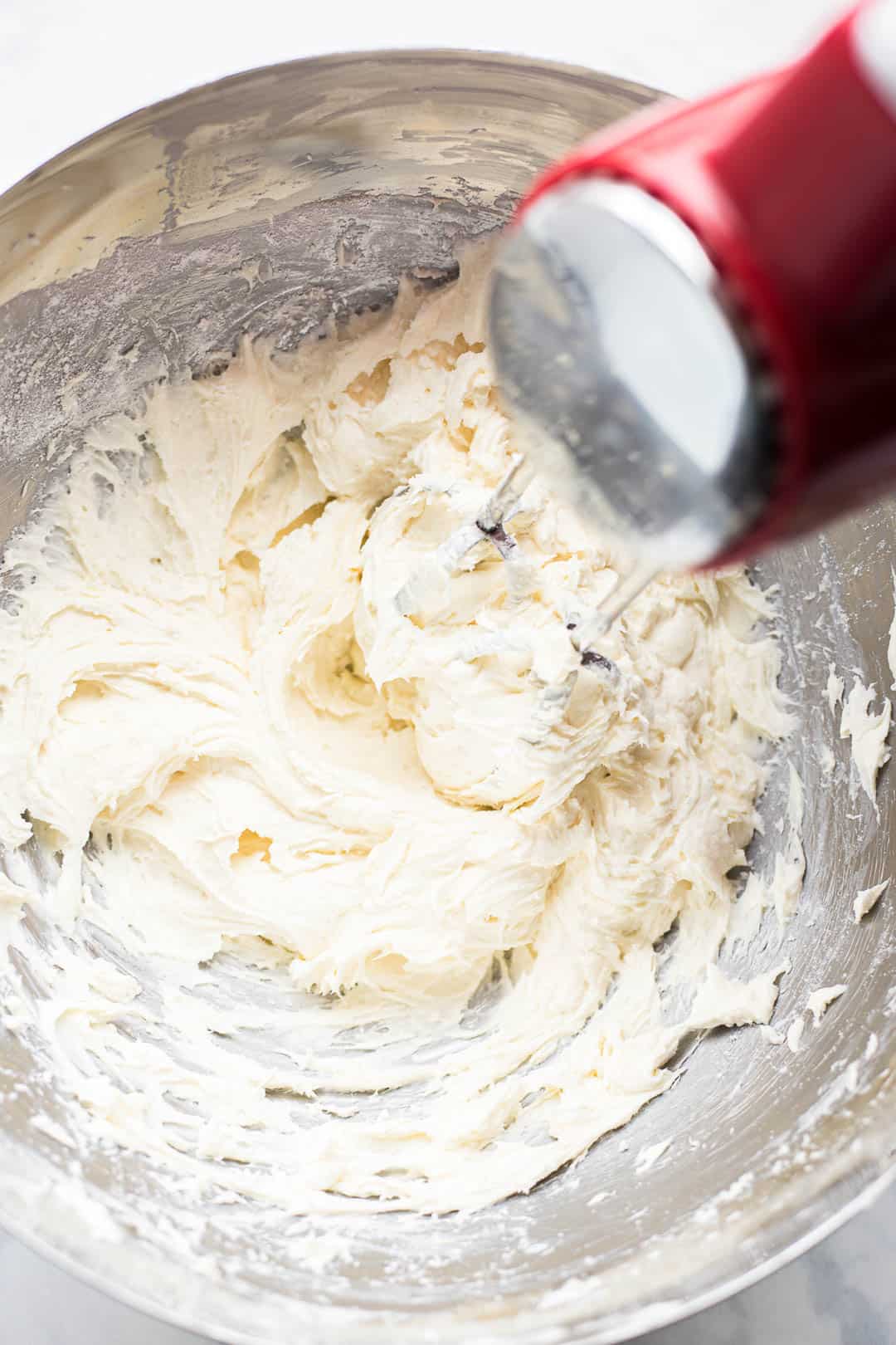 Process shot of beating cream cheese frosting in a bowl