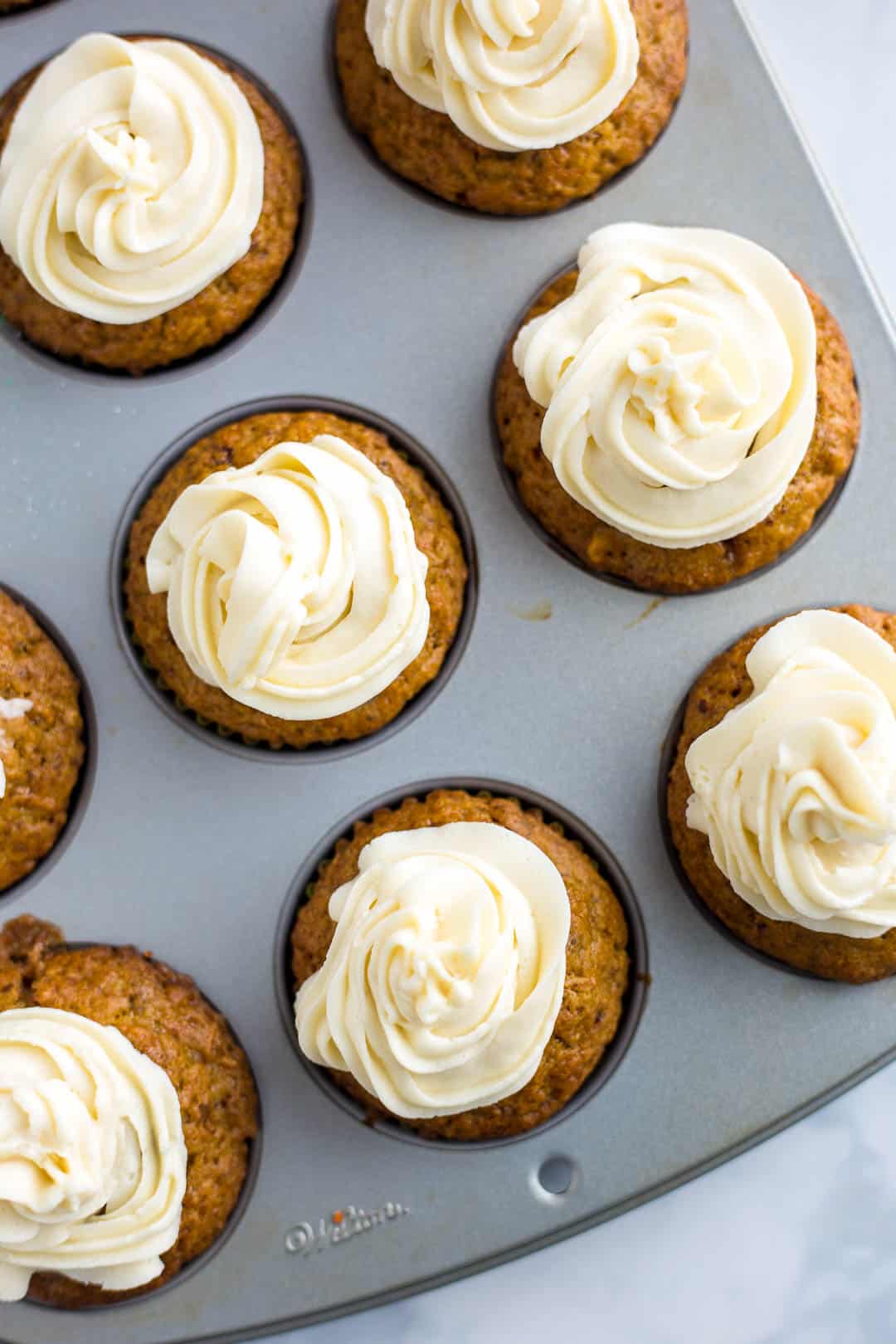 Just frosted Carrot Cake Cupcakes in a cupcake pan