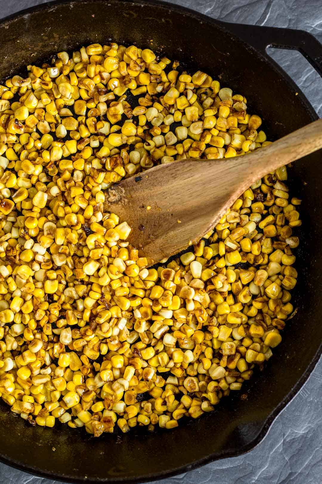 Process shot of browning corn kernels in a cast-iron skillet