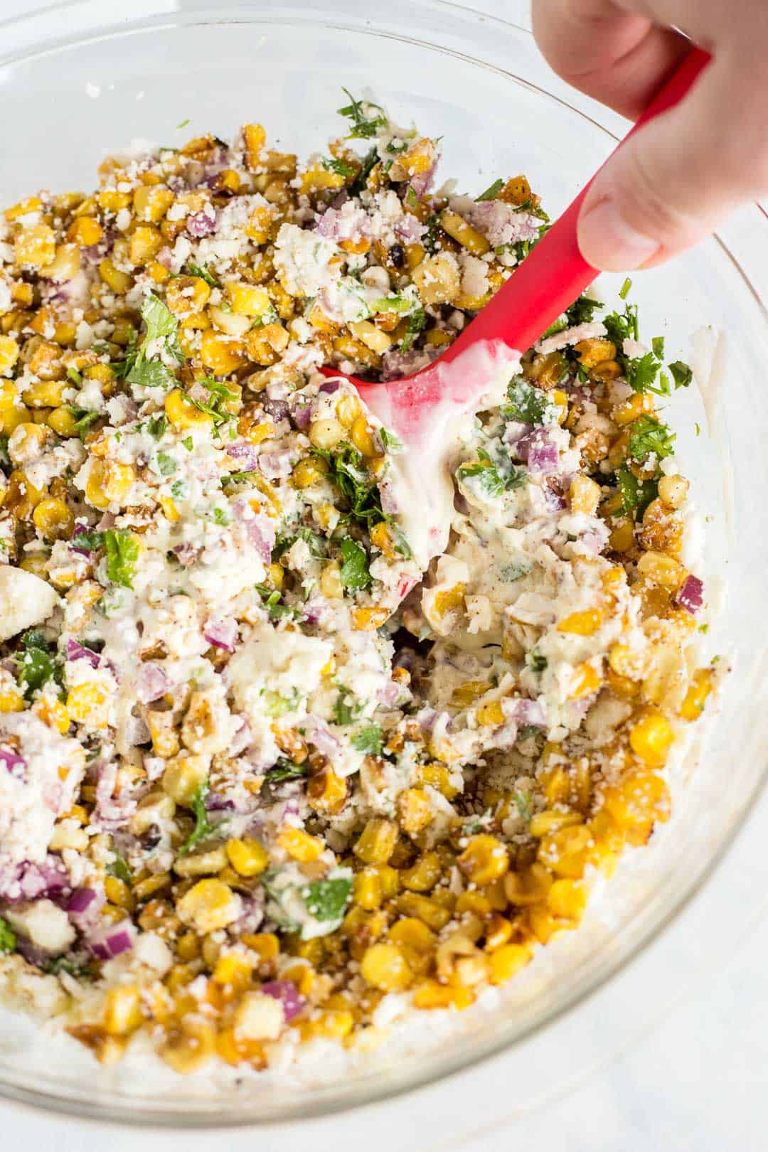 Process shot of stirring together Mexican Corn Salad in a bowl