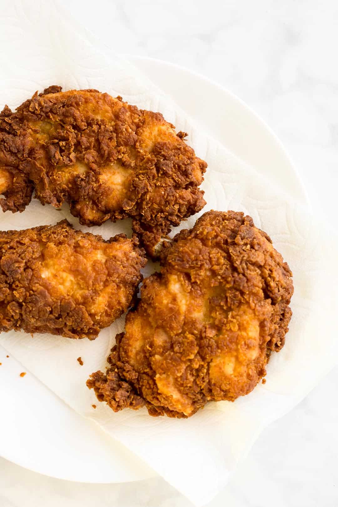 Fried breaded chicken draining on a plate