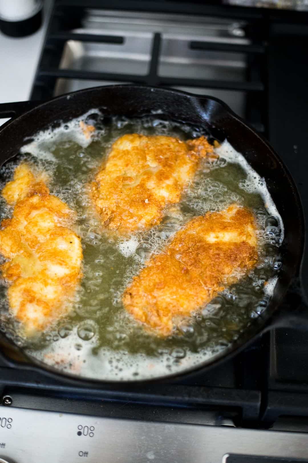 Process shot of breaded chicken frying in oil