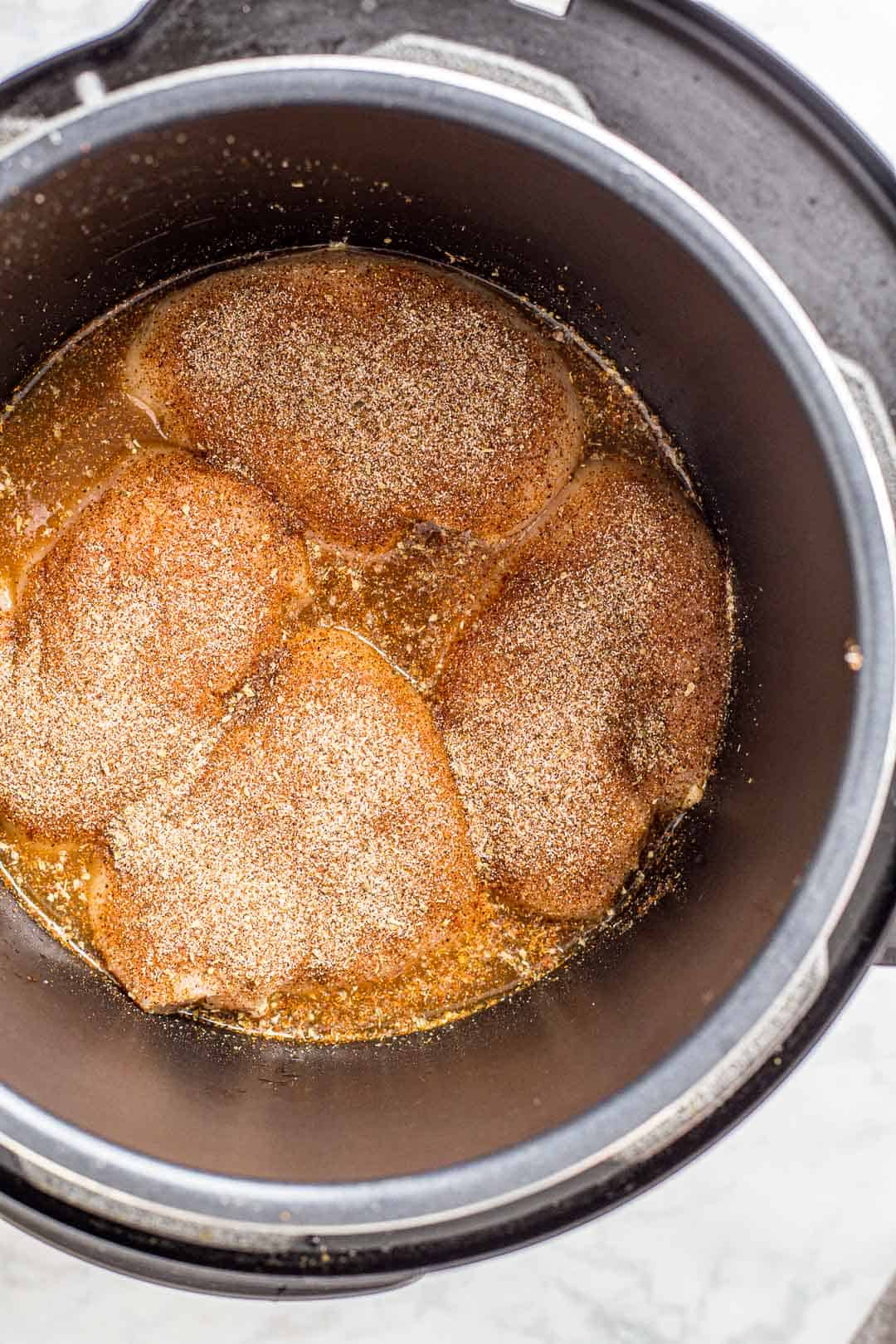 Chicken breasts covered in spices in a slow cooker ready to cook