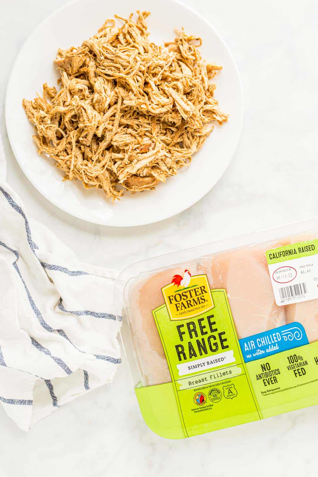 Package of Foster Farms chicken next to a plate of Slow Cooker Shredded Chicken