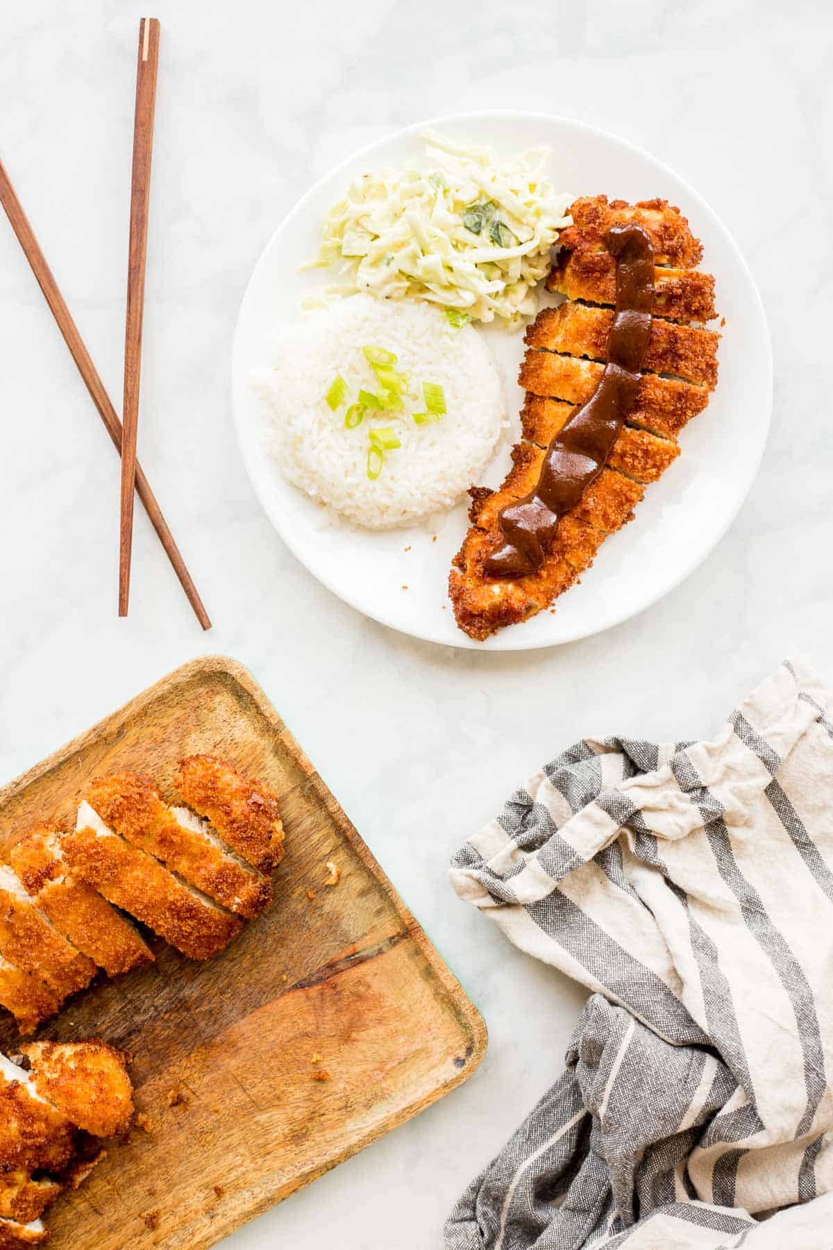 Slices of Chicken Katsu next to a prepared plate for serving