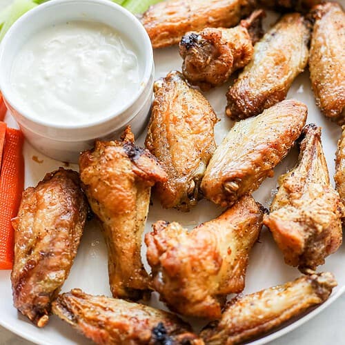 Close up of Air Fryer Chicken Wings on a plate with dipping sauce, carrots and celery