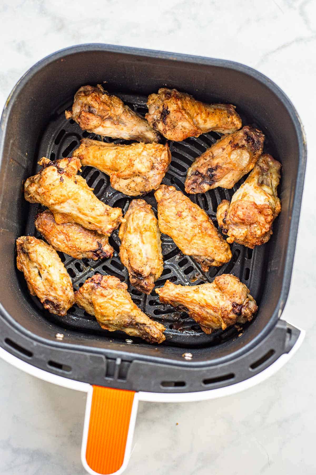 Crispy cooked chicken wings in a air fryer basket