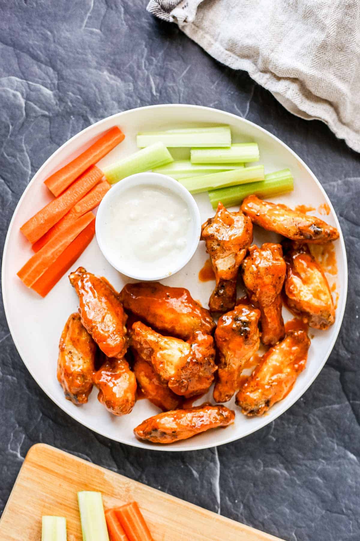 Air Fryer Buffalo Chicken Wings on a plate served with dressing, celery and carrots