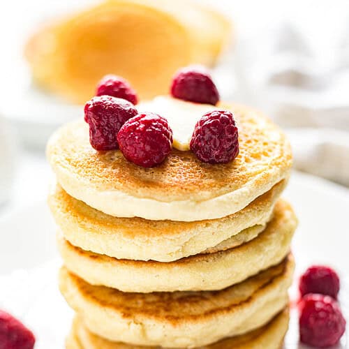 Stacked fluffy Keto Pancakes garnished with fresh raspberries
