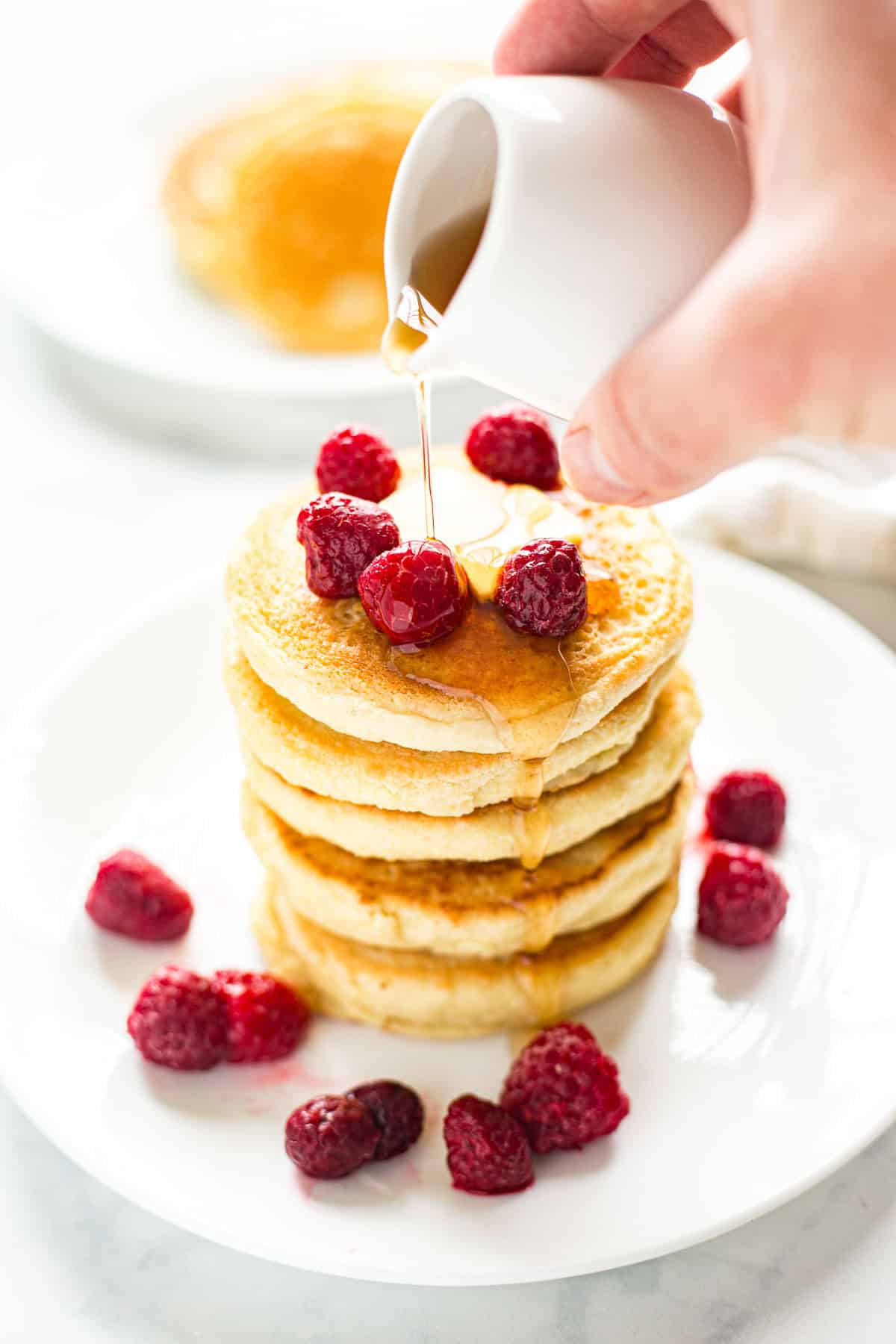 Pouring keto maple syrup over almond flour pancakes