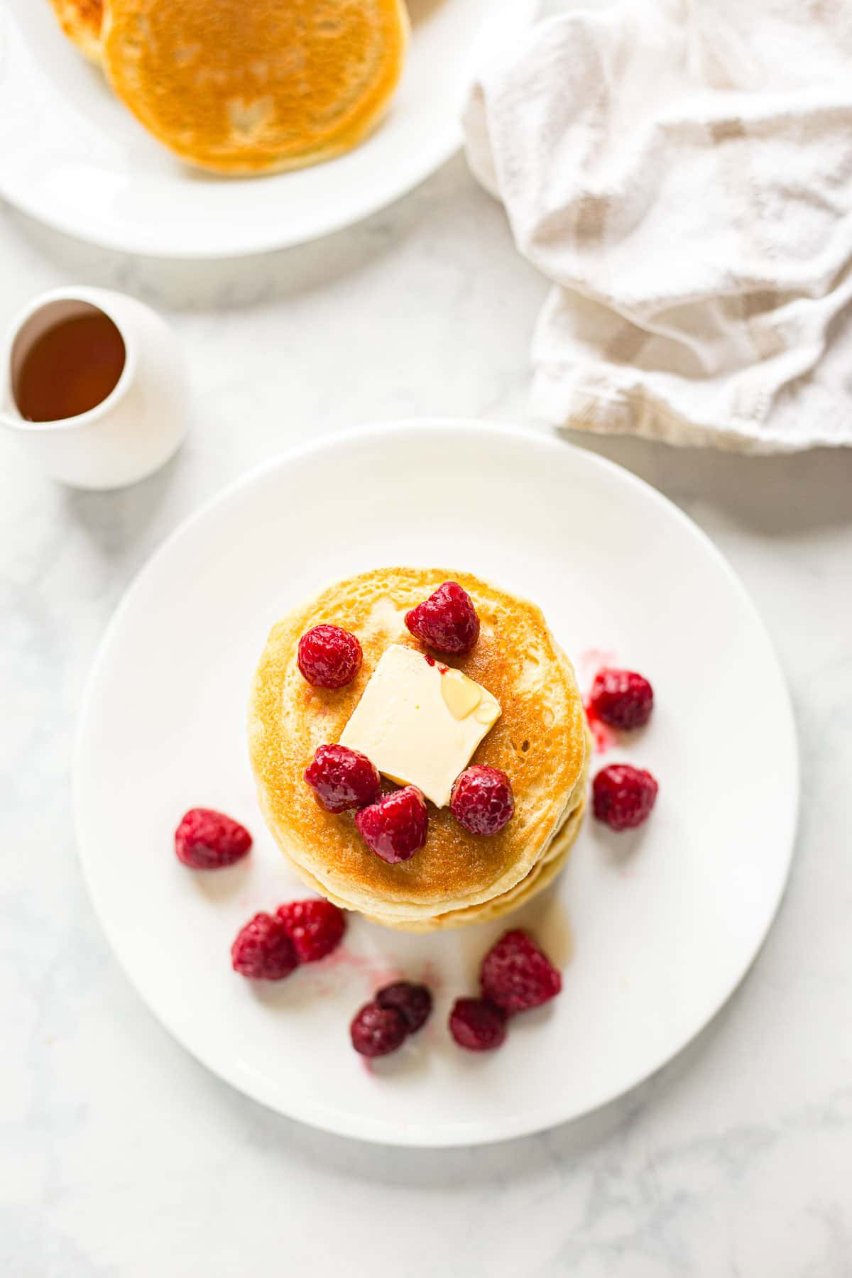 Overhead image of almond flour keto pancakes on plate garnished with fresh raspberries